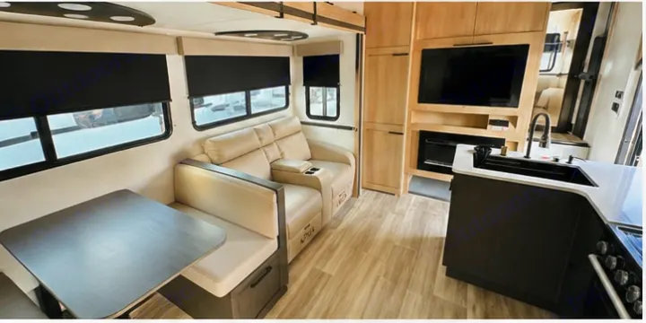 Modern rv rental interior featuring a dinette, recliner sofa, kitchen, and entertainment area. Ideal for travel & road trips.. Cruiser RV 32BH 2025
