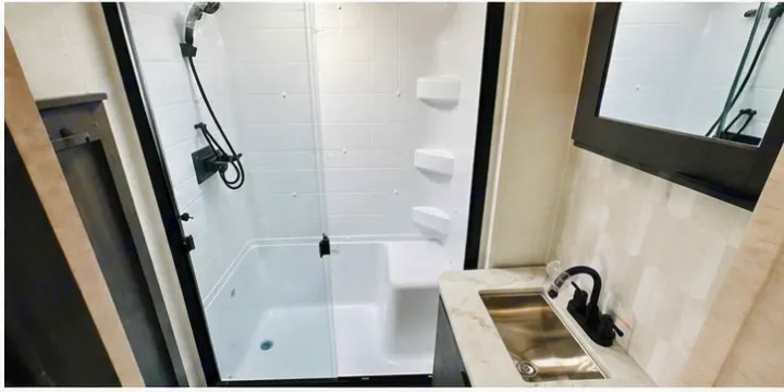 Clean and modern RV rental bathroom with a compact shower stall, built-in seat, vanity, and sink.. Cruiser RV 32BH 2025