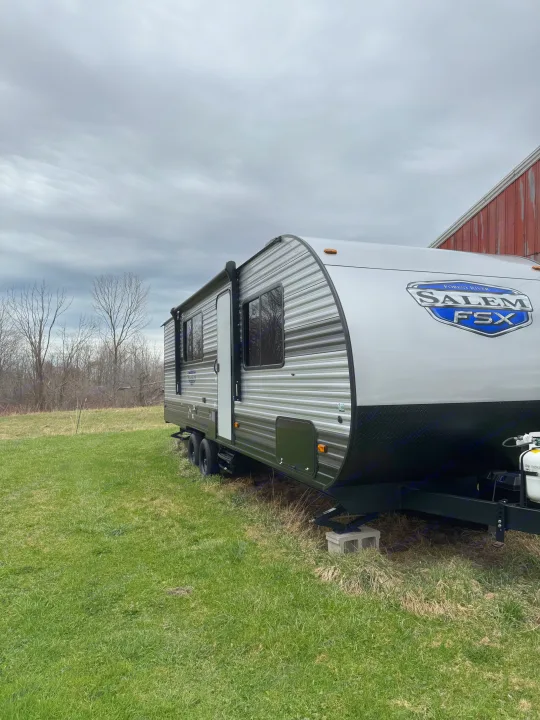A Forest River Salem FSX travel trailer, perfect for an RV rental, parked on grass under a cloudy sky with trees.. Forest River Salem FSX 2024