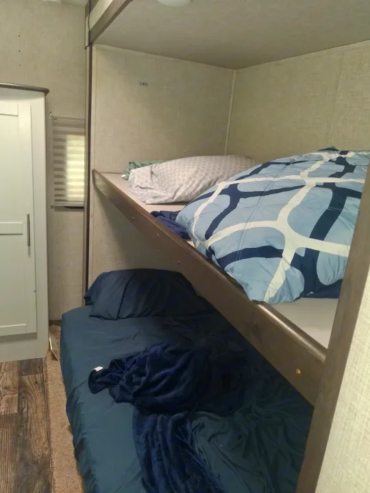 Cozy RV rental bunk beds with blue bedding offer compact, comfortable sleeping. Ideal for a family's travel accommodations.. Keystone RV Bullet Ultra Lite 2020