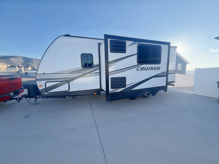 White and black "CRUISER" travel trailer, an ideal RV rental for camping adventures, with its slide-out extended.. Crossroads RV Cruiser Aire 2022