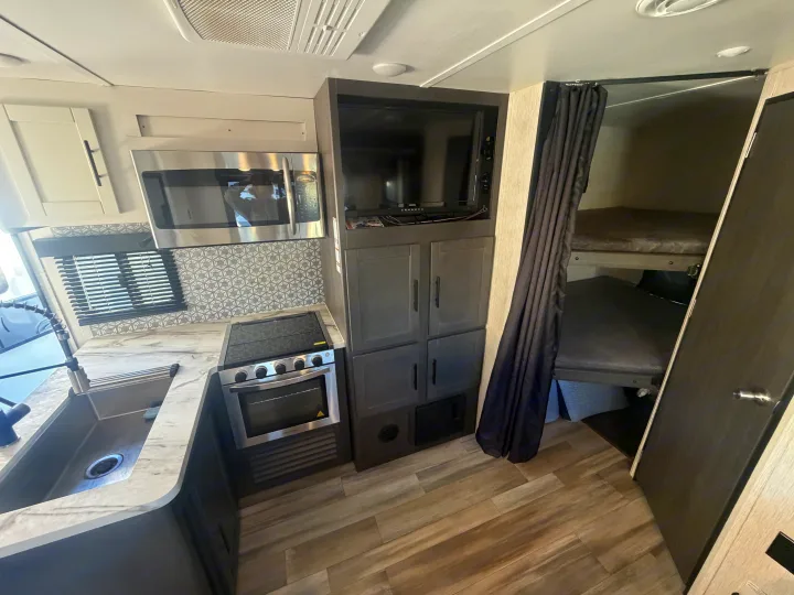 This RV rental's kitchen features a microwave, stove, oven, sink, TV, and cozy bunk beds for your adventure.. Crossroads RV Cruiser Aire 2022