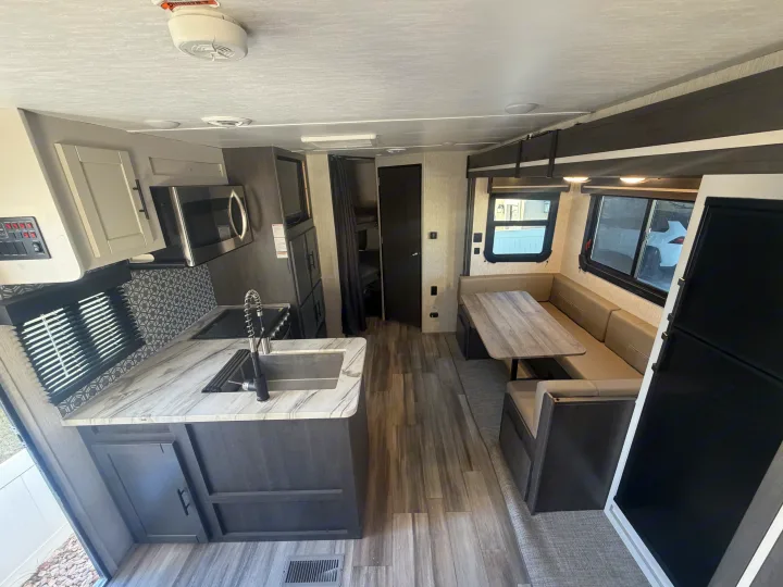 Spacious rv rental interior featuring a modern kitchen, dinette, and bunk beds. Wood-look flooring and neutral decor.. Crossroads RV Cruiser Aire 2022