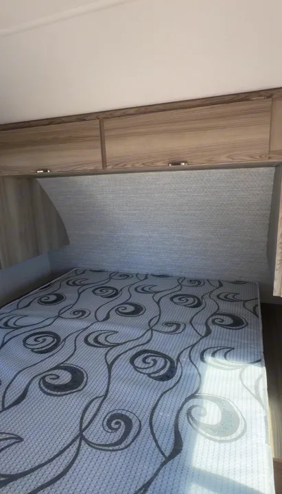 RV rental bedroom with a patterned mattress, overhead cabinets, and a textured headboard for compact comfort.. Forest River Salem FSX 2024