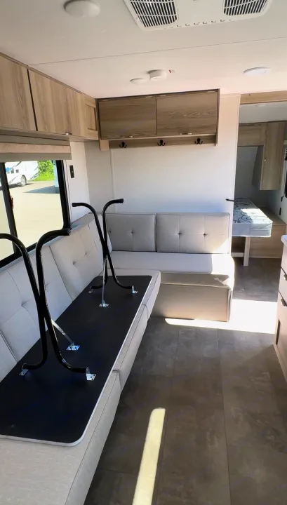 Bright rv rental interior: dinette with folded black table on light gray seating, overhead cabinets, and a rear bunk.. Forest River Salem FSX 2024