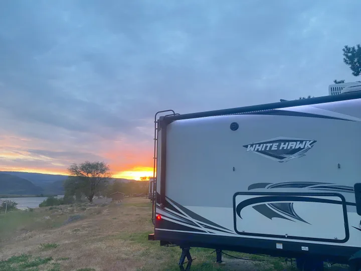 Golden hour at a scenic campsite with a White Hawk rv rental, highlighting a beautiful sunset over mountains and river.. Jayco White Hawk 2020
