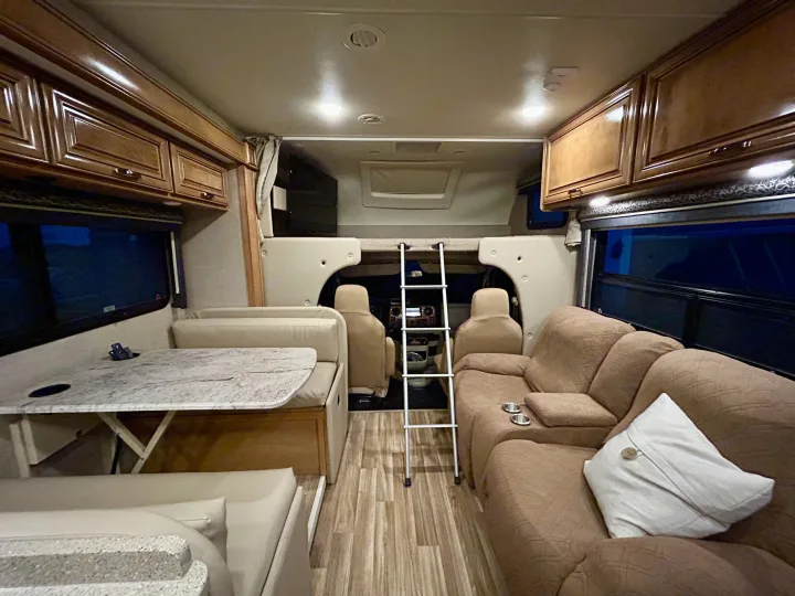 Inviting motorhome RV rental interior. Features a dinette, couch, and bunk for comfy travel adventures.. Thor Quantum 2017