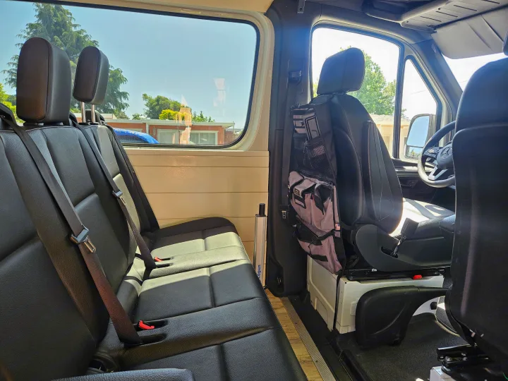 RV rental interior: comfy black passenger seats, side window, Lagun table mount, & handy storage bag. Ready for your journey!. Mercedes Benz Sprinter 2020