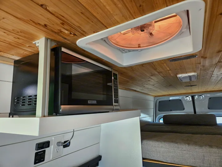 rv rental interior: microwave, ceiling fan, and controls under a wood ceiling, with a cozy bed in view.. Mercedes Benz Sprinter 2020