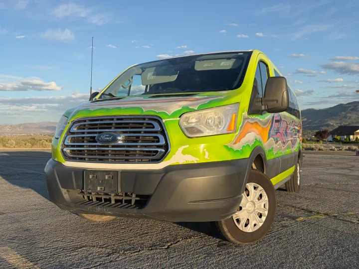 This custom-painted Ford Transit van, an eye-catching rv rental, features vibrant graffiti art, parked against a scenic mountain backdrop.. Ford Transit 2017