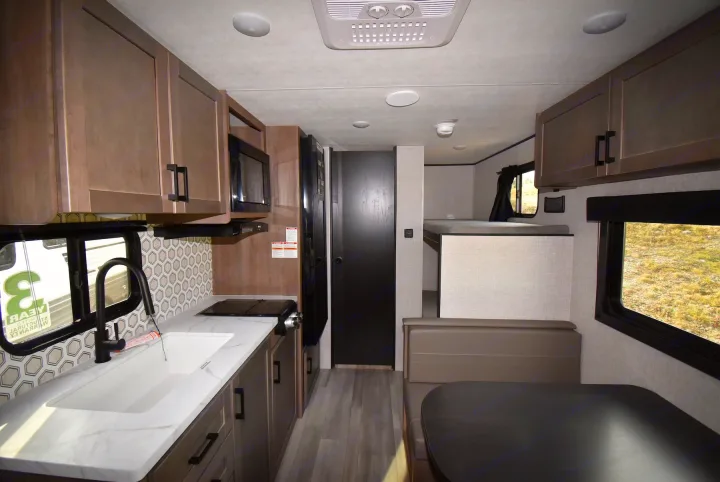 Modern RV rental interior featuring a compact kitchen, dining booth, and bunk beds for family travel adventures.. Starcraft Autumn Ridge 2025