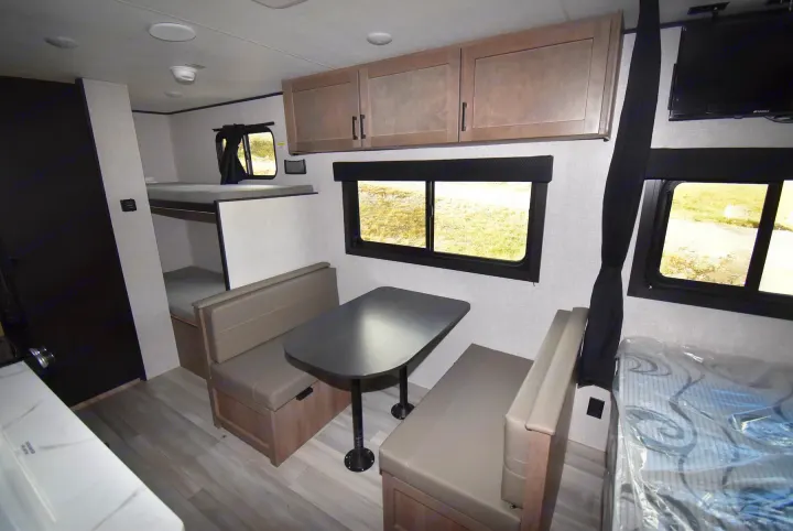 Cozy rv rental interior featuring a dinette, bunk beds, overhead cabinets, and bright windows for a comfortable stay.. Starcraft Autumn Ridge 2025