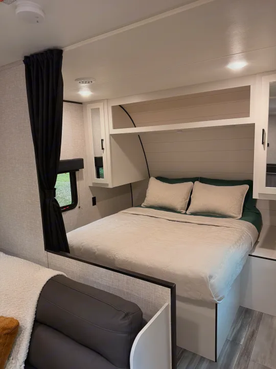 Cozy RV rental bedroom with a white patterned bed, dark green accents, overhead storage, and modern decor. Ideal for travel.. Jayco Jay Flight SLX 2024