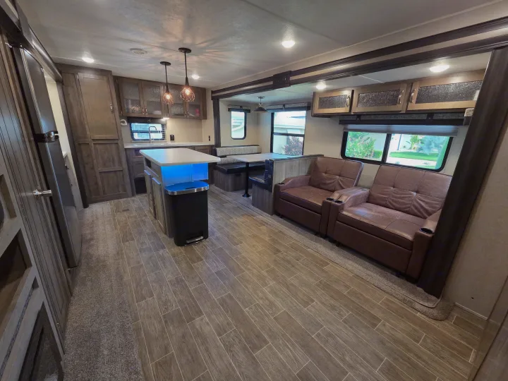 Spacious RV rental interior showing a modern kitchen island, cozy recliners, and a dinette area.. Forest River Palomino Puma 2020