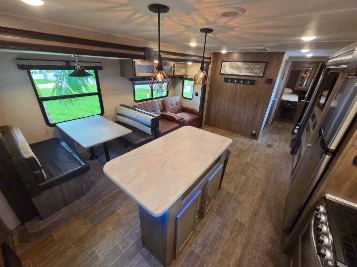 Spacious RV rental interior featuring a kitchen island, dinette, recliner chairs, and modern amenities for a comfortable journey.. Forest River Palomino Puma 2020