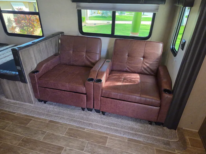 Cozy RV rental interior with two brown leather recliners and large windows. Perfect for comfortable travel.. Forest River Palomino Puma 2020