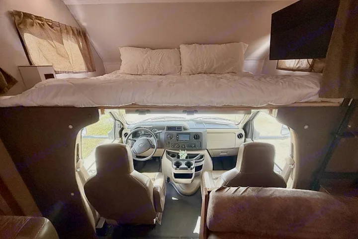 Inside this rv rental: a spacious bunk bed overlooks the Ford cab, dashboard, and front seats, plus a side-mounted TV.. Forest River Sunseeker 2016