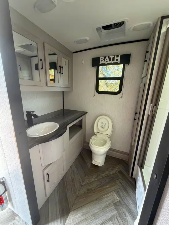 Modern RV rental bathroom: features a vanity with sink, toilet, and shower. Clean, compact interior for your comfortable travels.. Heartland RVs Mallard 2023