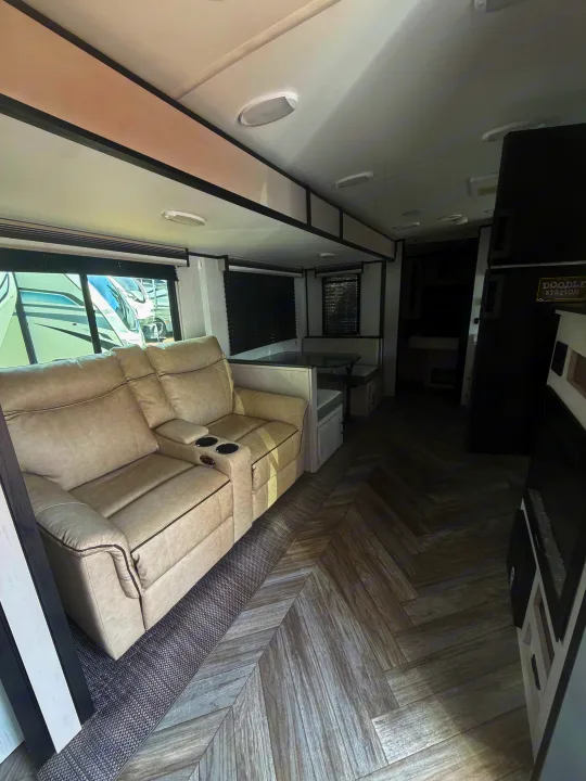 Bright RV rental interior with comfortable recliners, dining booth, and modern herringbone flooring, ready for your adventures.. Heartland RVs Mallard 2023
