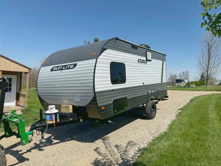 Sun Lite travel trailer, ready for rv rental adventures. This travel trailer is parked on a gravel driveway, ideal for camping trips.. Sunset Park RV Sun Lite LTD 2025