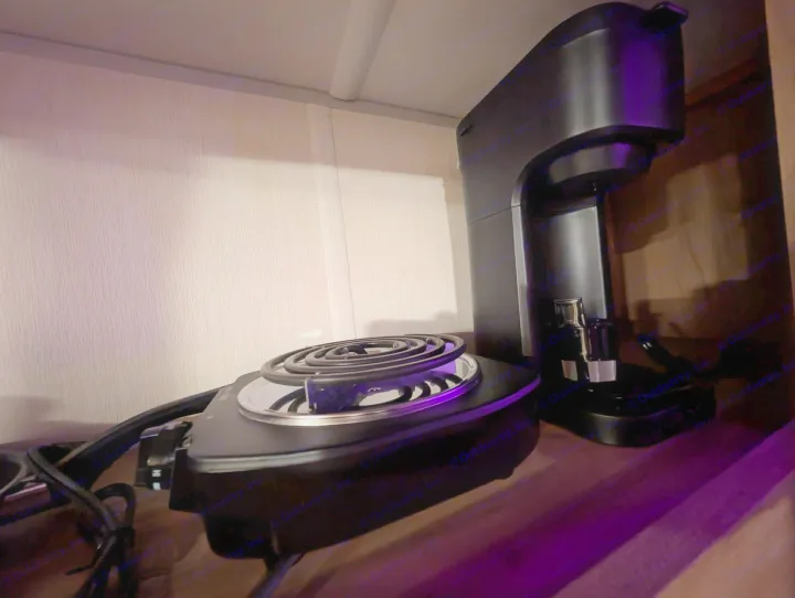Compact electric hot plate (underlit with purple) & coffee maker on a shelf, often found in an RV rental.. Forest River Cherokee Wolf Pup 2025