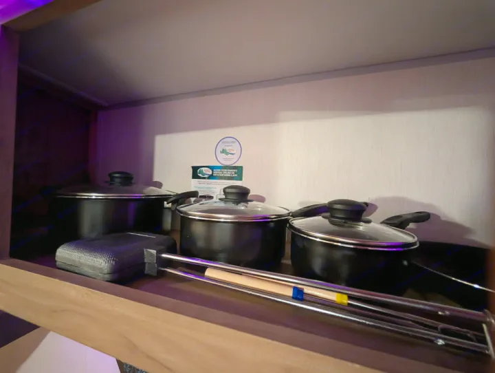 Cooking essentials for your RV rental: three pots with lids, a grill pan, and skewers neatly arranged in a cabinet.. Forest River Cherokee Wolf Pup 2025