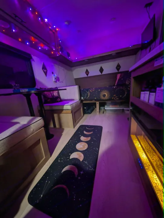 Inside a vibrant **rv rental**: purple lighting illuminates a moon phase rug, celestial bed, and cozy dinette.. Forest River Cherokee Wolf Pup 2025