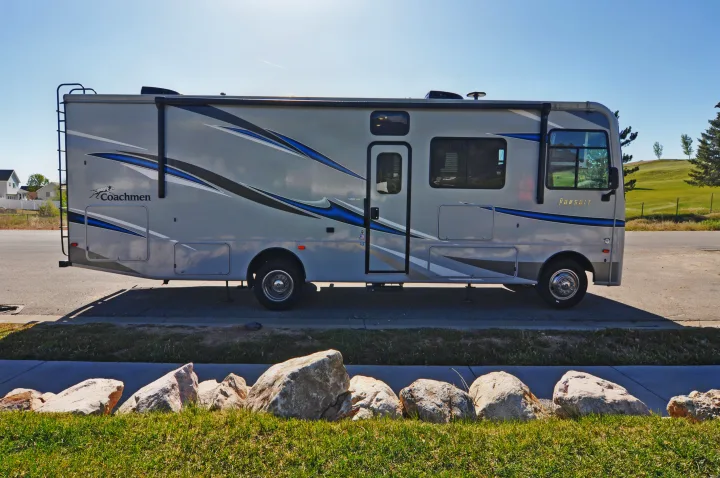 This Coachmen Pursuit rv rental, a large gray motorhome with blue accents, is parked outdoors, ready for a travel adventure.. Coachmen Pursuit 2022