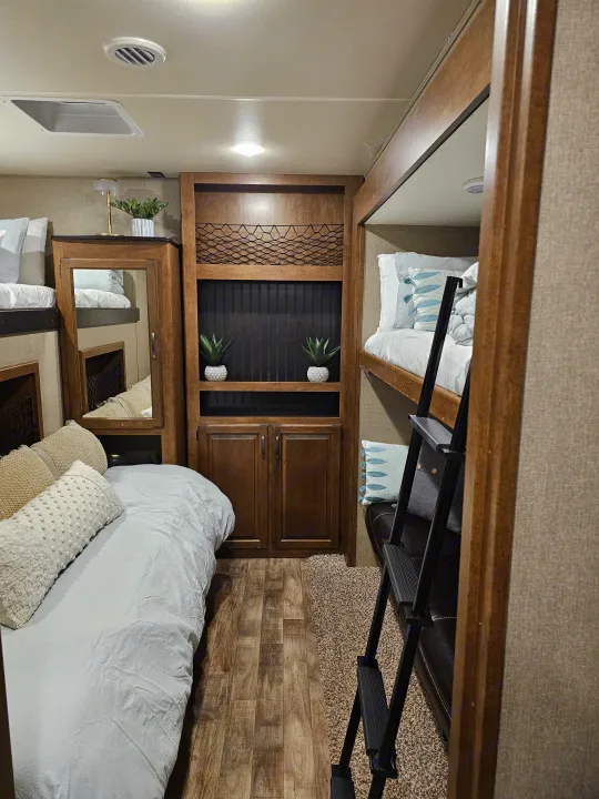 RV rental interior featuring cozy bunk beds, a main sleeping area, built-in storage, and a ladder.. Grand Design Reflection 2016