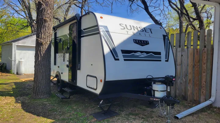 White Sunset Trail RV rental, a travel trailer, parked outdoors. Features a propane tank, ready for camping adventures.. Crossroads RV Sunset Trail 2026