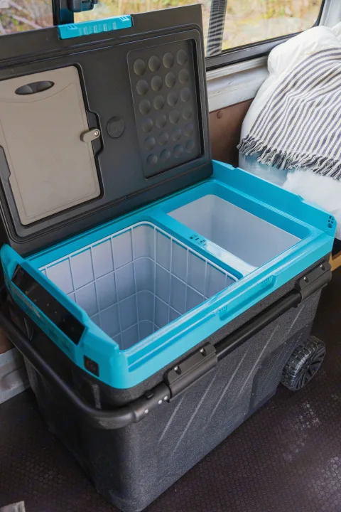 Dual-zone electric cooler with open lid & built-in cutting board inside an rv rental, ready for travel & camping.. Toyota Hiace 2005