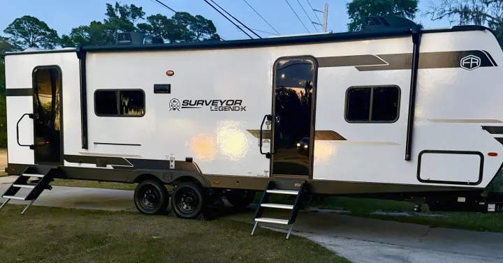 This white Surveyor LegendX travel trailer with open doors and extended stairs is an excellent RV rental choice for your next adventure.. Forest River Surveyor Legend X 2025