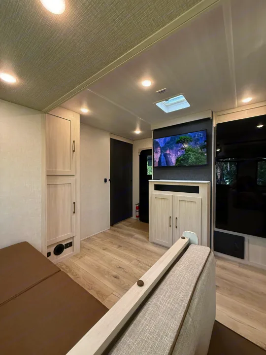 Cozy RV rental interior with modern decor, showcasing a mounted TV, cabinetry, light wood flooring, and comfortable seating.. Forest River Surveyor Legend X 2025
