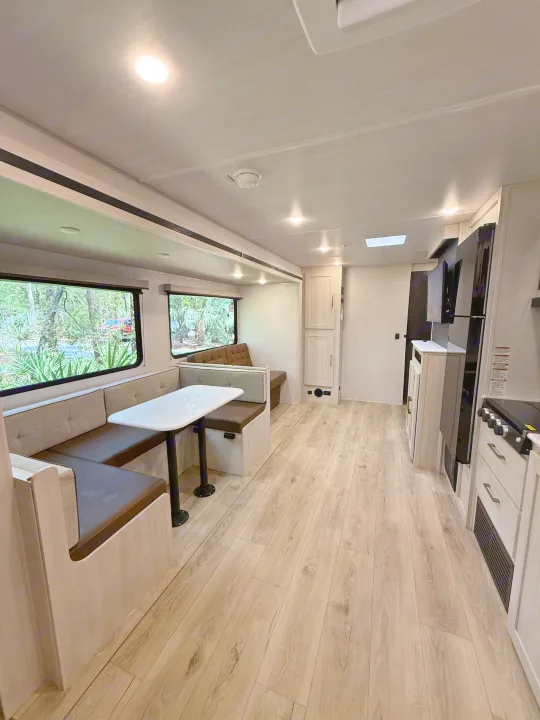 Spacious RV rental interior featuring a bright dinette with large windows, light wood floors, and a functional kitchen area.. Forest River Surveyor Legend X 2025
