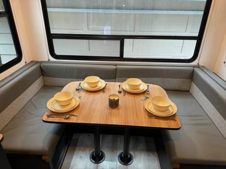 This inviting RV rental dinette features a grey U-shaped booth and wood table set for four, perfect for cozy meals on your road trip.. Keystone RV Springdale 2022