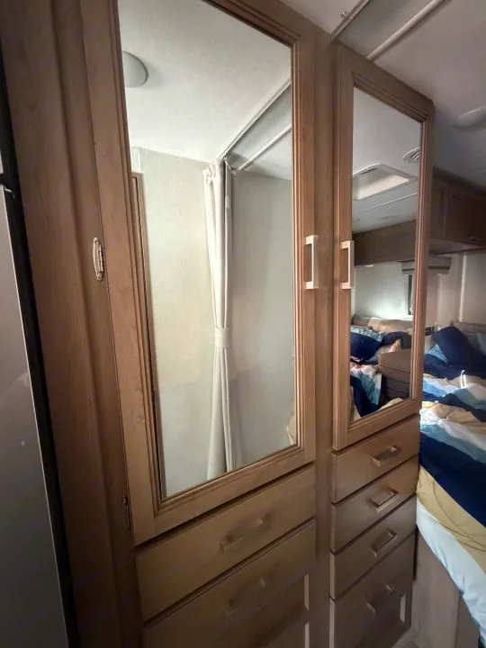 RV rental interior: Mirrored closets reflecting a bed and a shower, showcasing compact yet functional living space.. Thor Vegas 2026