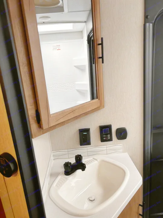 Compact rv rental bathroom with corner sink, medicine cabinet, wall controls, and reflected shower stall.. Forest River Campsite Reserve 2024