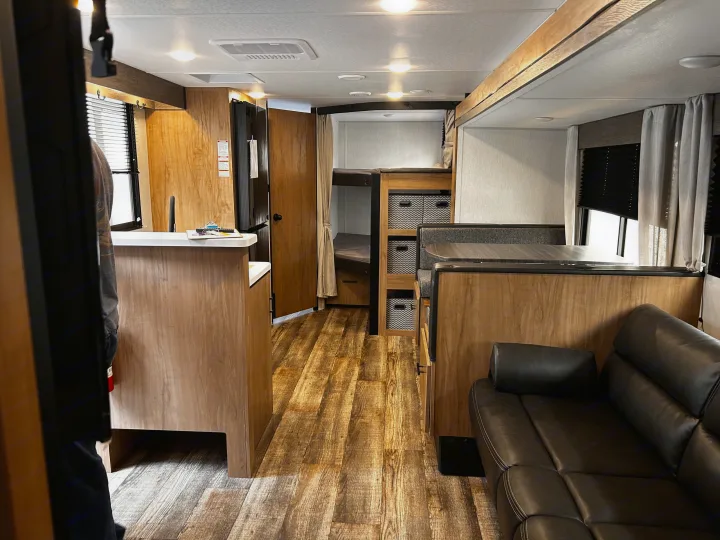Spacious RV rental interior with a modern kitchen, dinette, comfortable sofa, and bunk beds, perfect for family adventures.. Forest River Campsite Reserve 2024