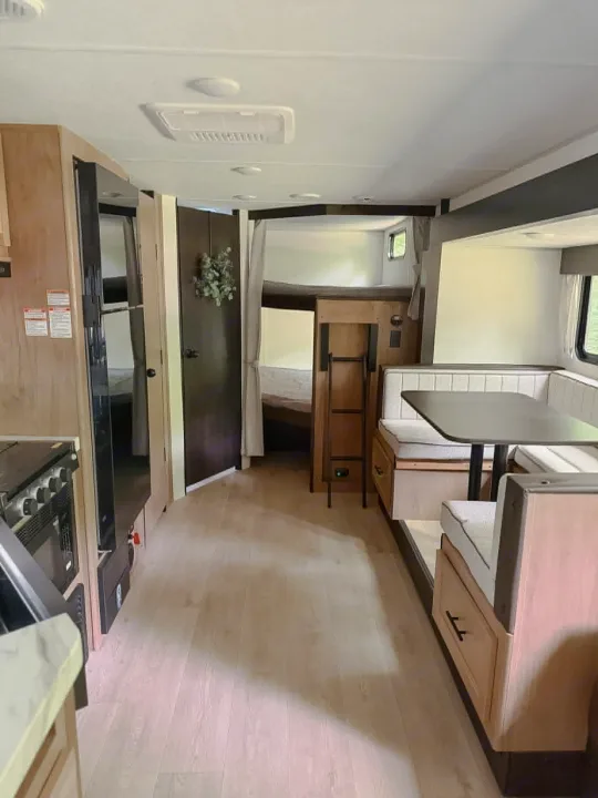 Explore this modern RV rental's interior: a well-equipped kitchen, comfy bunk beds, and a cozy dinette setup.. Forest River Cherokee Grey Wolf 2025