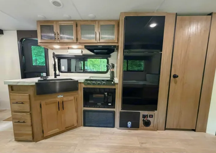Modern RV rental kitchen interior featuring a large sink, stove, microwave, fridge, and ample cabinets, perfect for travel.. Forest River Cherokee Grey Wolf 2025