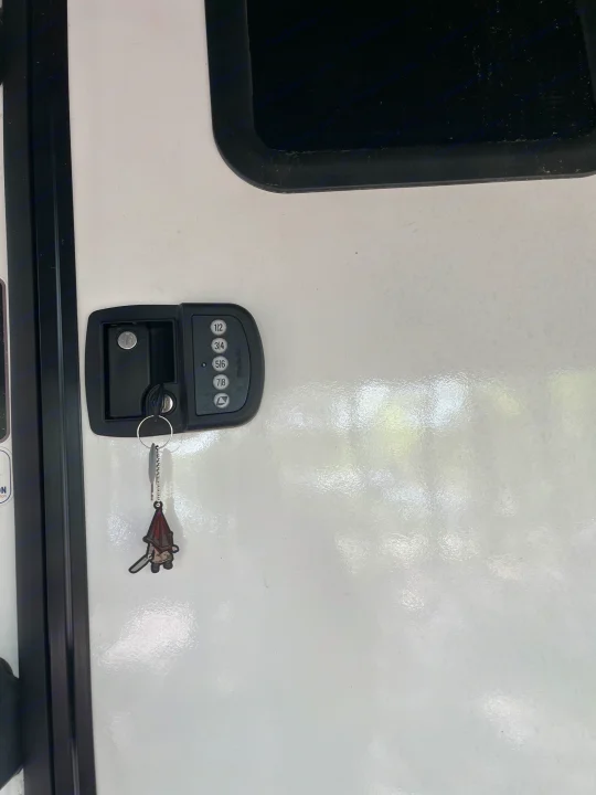 RV rental door featuring a keyless entry lock with a key and a unique Pyramid Head keychain.. Grand Design Imagine 3100RD 2025