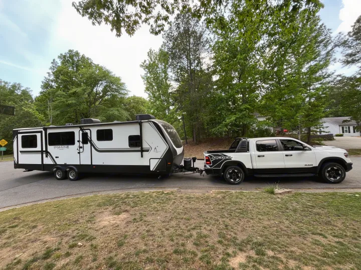 White Ram Rebel truck towing a sleek Grand Design Imagine travel trailer, perfect for your next rv rental adventure or camping trip.. Grand Design Imagine 3100RD 2025