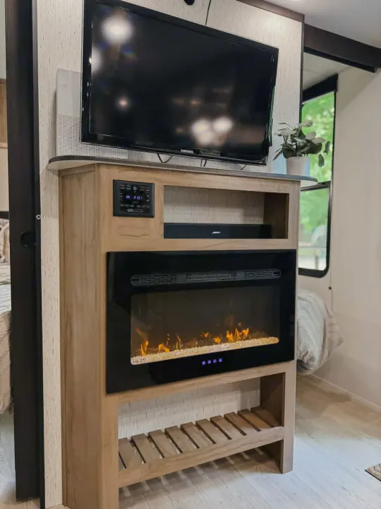Cozy RV rental interior featuring a wood entertainment center with a TV, soundbar, and glowing electric fireplace.. Forest River Cherokee Grey Wolf 2025