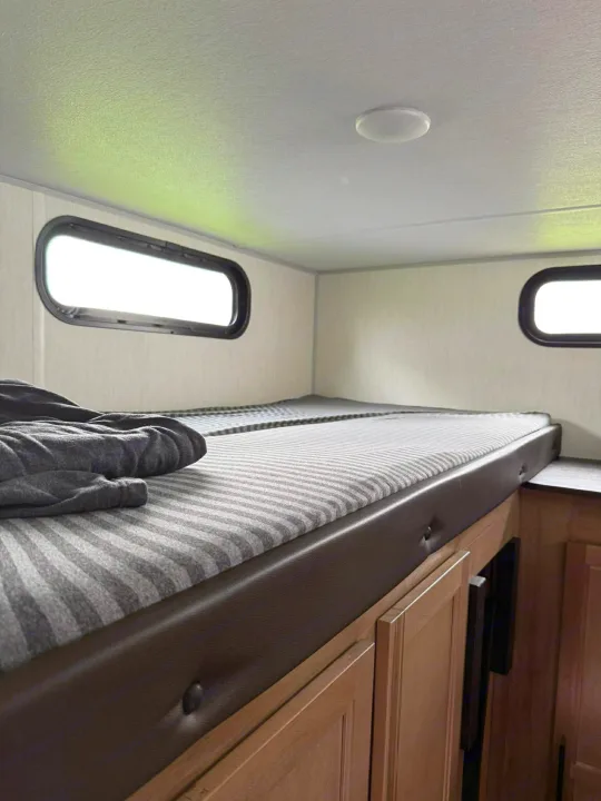 Cozy bunk beds with striped mattresses and small windows in a bright rv rental interior.. Forest River Cherokee Grey Wolf 2025