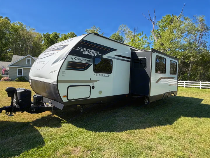 Northern Spirit by Coachmen rv rental travel trailer parked on a sunny green lawn with an extended slide-out.. Coachmen 2963BH 2023