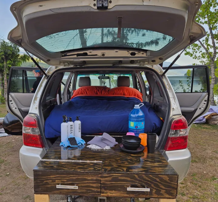 Car camping SUV setup with a cozy bed, pull-out kitchen, and scenic lake view for your next outdoor adventure or RV rental.. Toyota Highlander 2004
