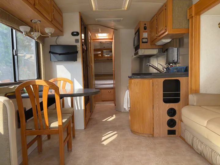 Spacious rv rental interior showing a dining area, full kitchen, and a glimpse into the bedroom, bathed in natural light.. Airstream Airstream Motorhome 2006