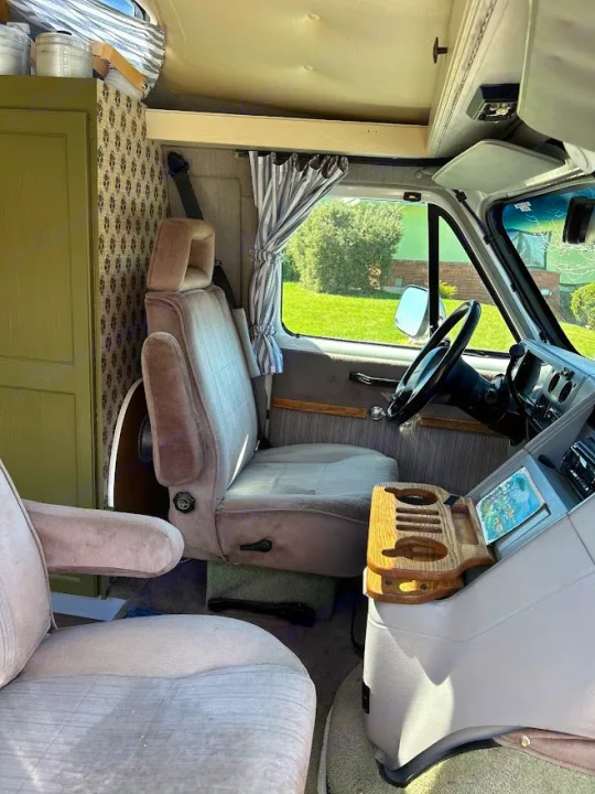 Customized RV rental interior, featuring driver's area, custom seating, steering wheel, and front cabin with striped curtains.. Roadtrek 190 Popular 1995