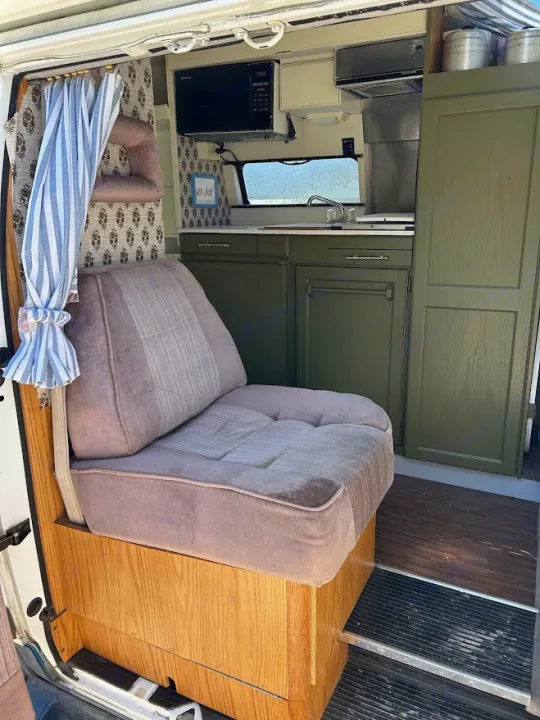Cozy RV rental interior with olive green kitchenette (microwave, sink) and plush seating. Perfect camper van setup!. Roadtrek 190 Popular 1995
