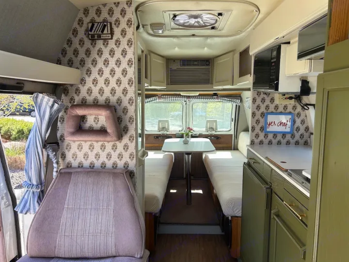 Step inside this charming rv rental! Features a compact kitchen, dining table, cozy beds, and unique patterned wallpaper.. Roadtrek 190 Popular 1995